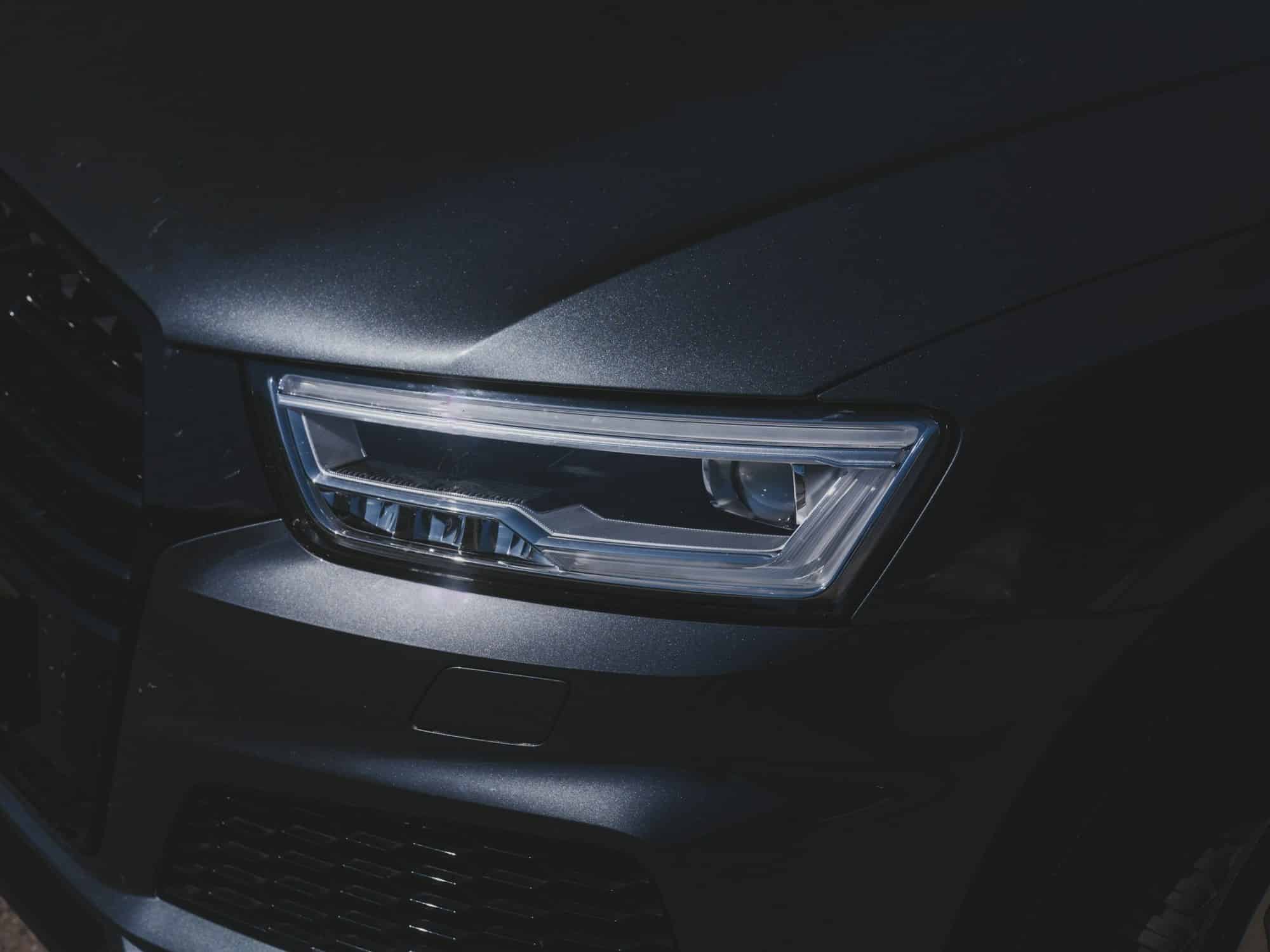 A close-up of a dark car headlight — illustrative photography